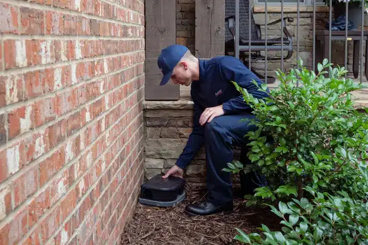 Mouse and rat control technician installing rodent bait outside randleman NC house